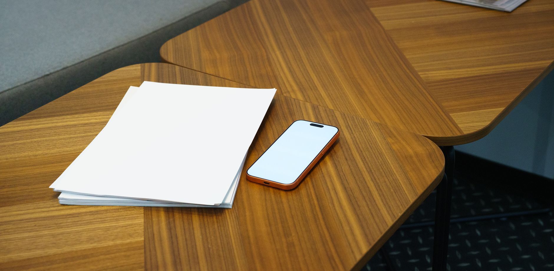 A tidy office desk with a smartphone and a stack of papers, ideal for business settings.